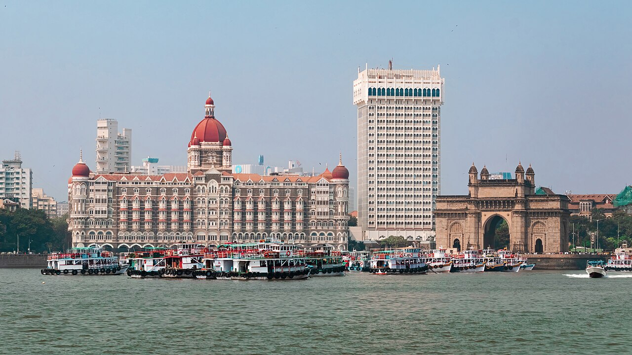 The Taj Palace hotel and the Gateway of India across Mumbai harbour, with ferries in front